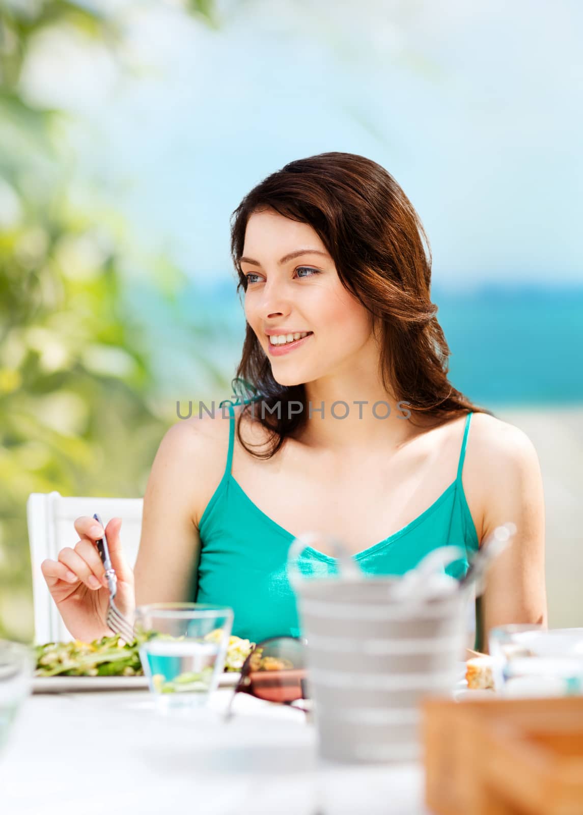 summer holidays and vacation - girl eating in cafe on the beach