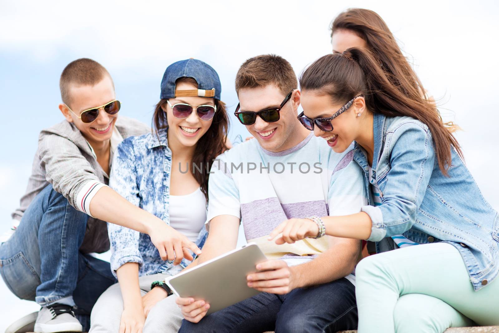 summer holidays, teenage and technology concept - group of teenagers looking at tablet pc