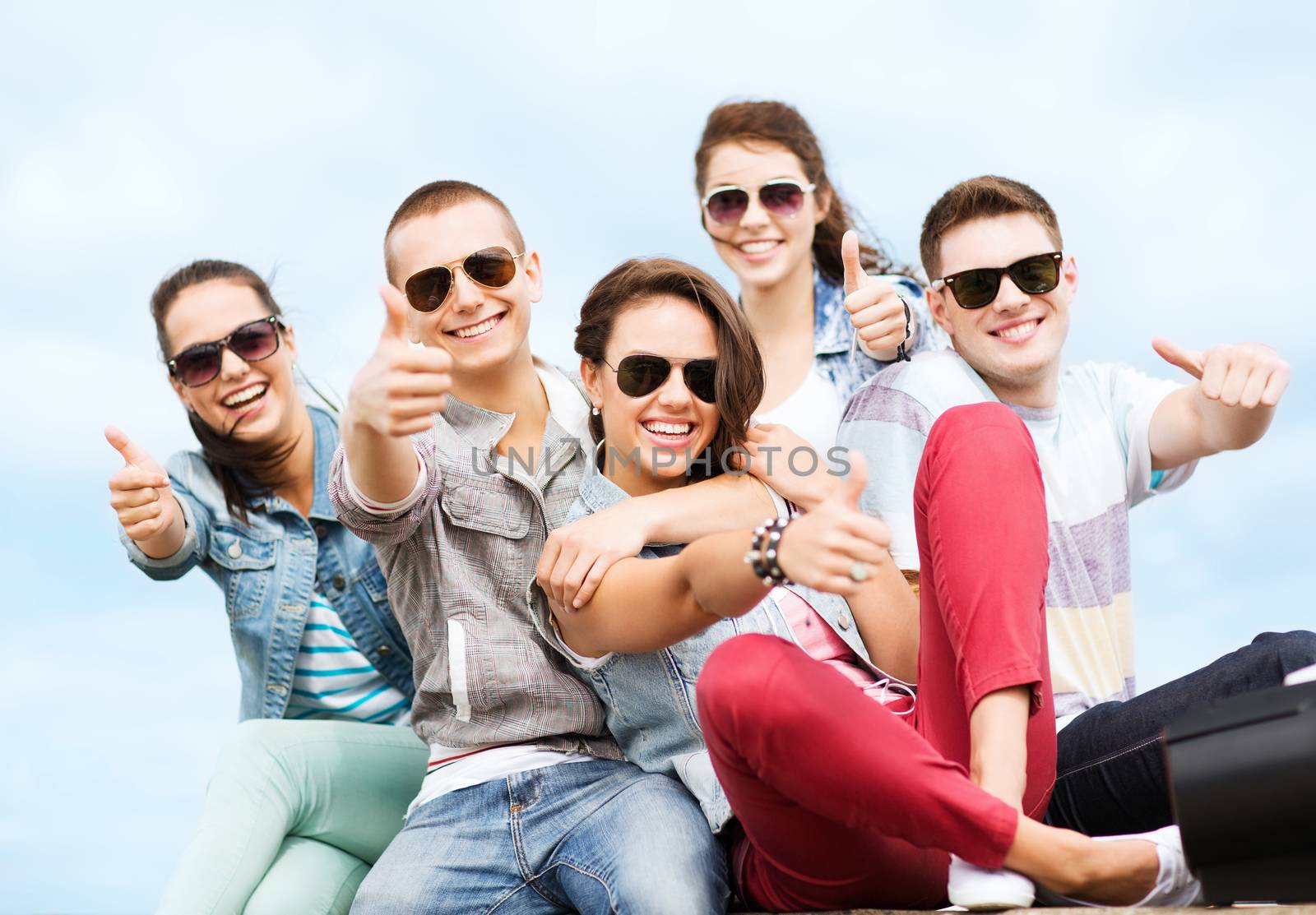 summer holidays and teenage concept - group of teenagers showing thumbs up outside