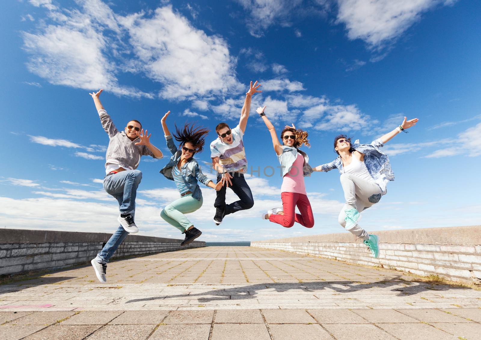 summer, sport, dancing and teenage lifestyle concept - group of teenagers jumping