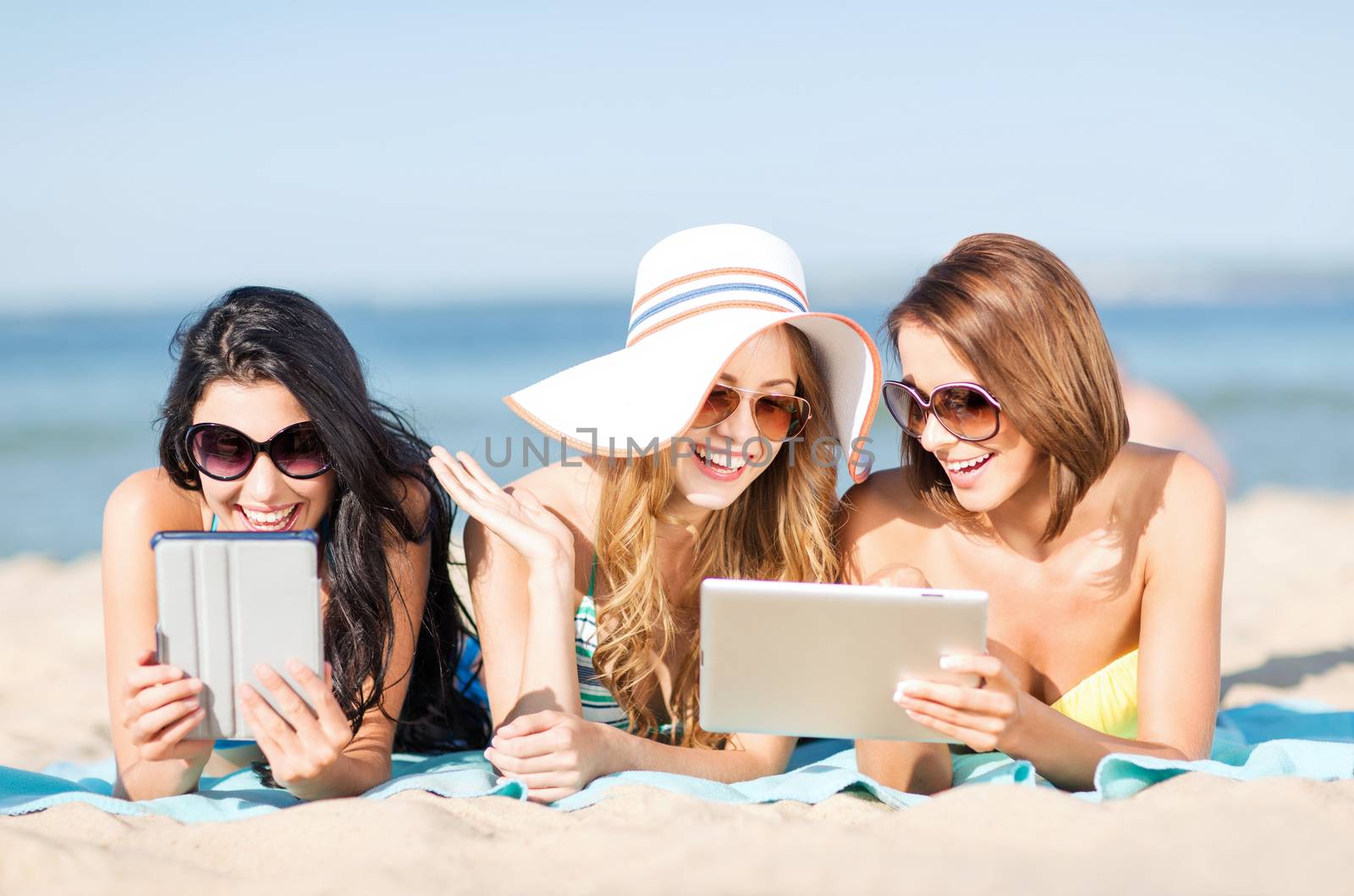 girls with tablet pc on the beach by dolgachov