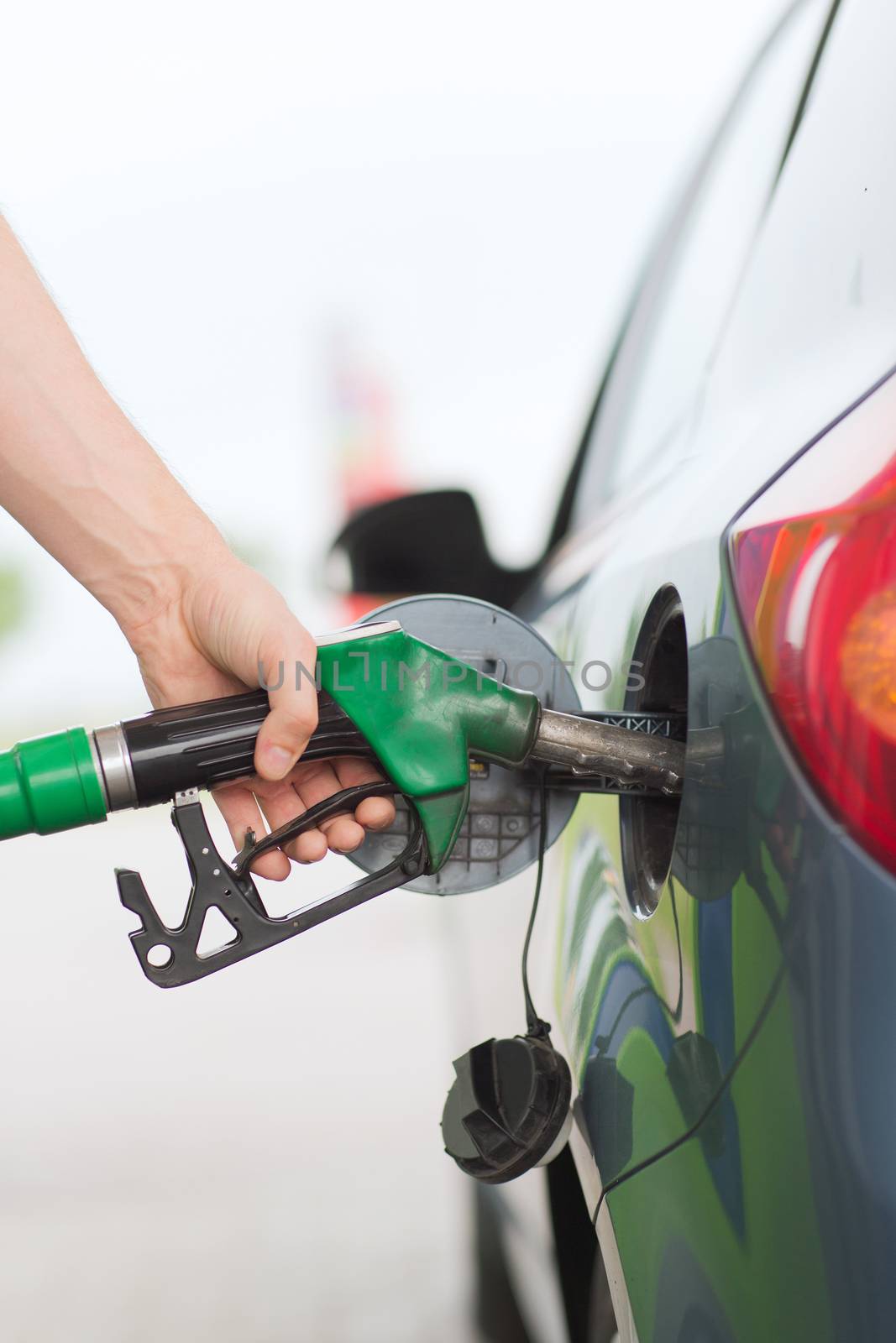 man pumping gasoline fuel in car at gas station by dolgachov