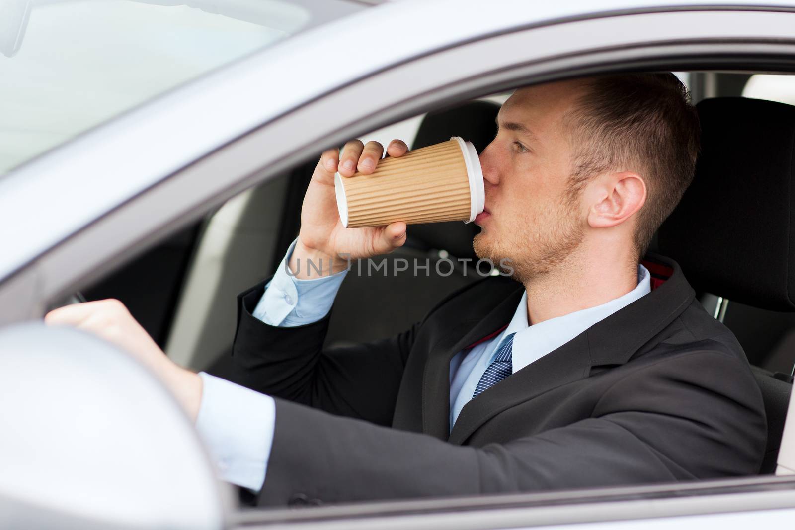 man drinking coffee while driving the car by dolgachov
