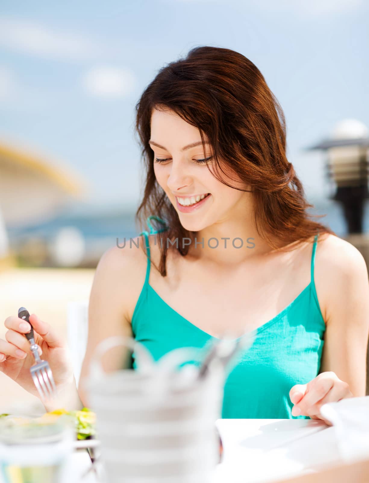 girl eating in cafe on the beach by dolgachov