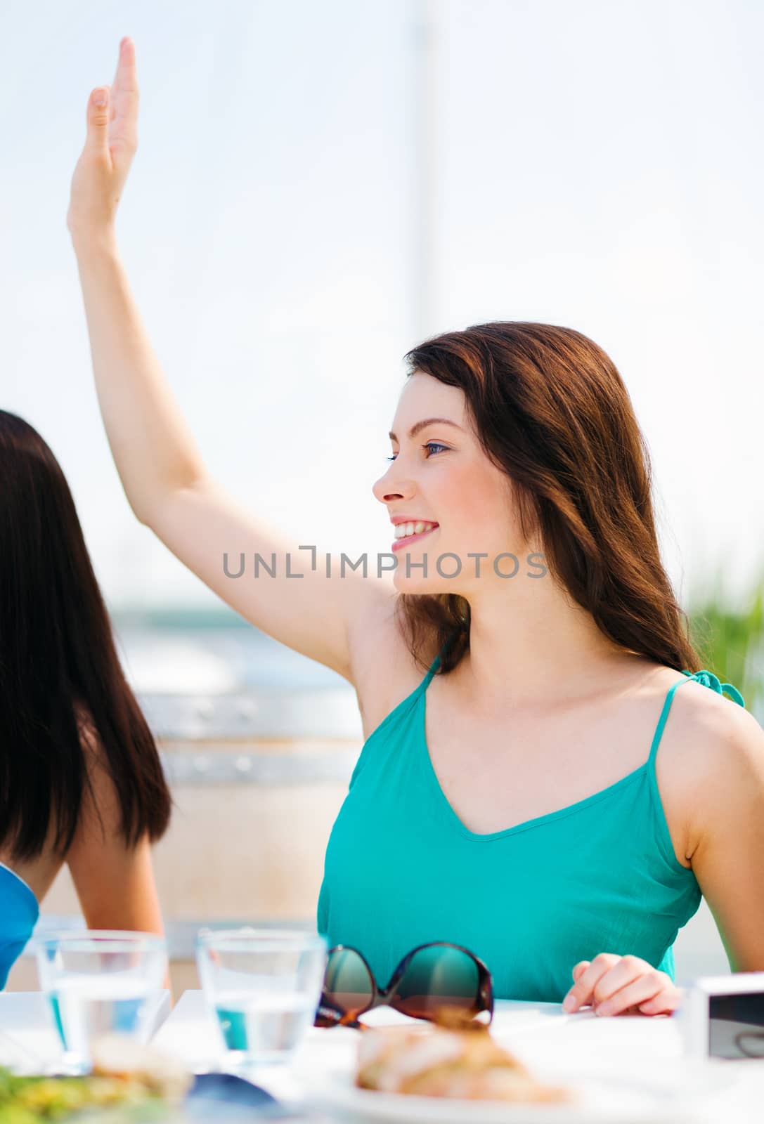 summer holidays and vacation - girl waving hand in cafe on the beach