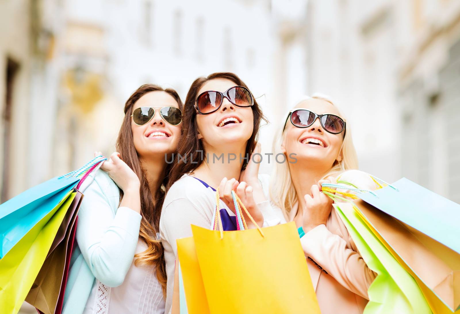 shopping and tourism concept - beautiful girls with shopping bags in ctiy