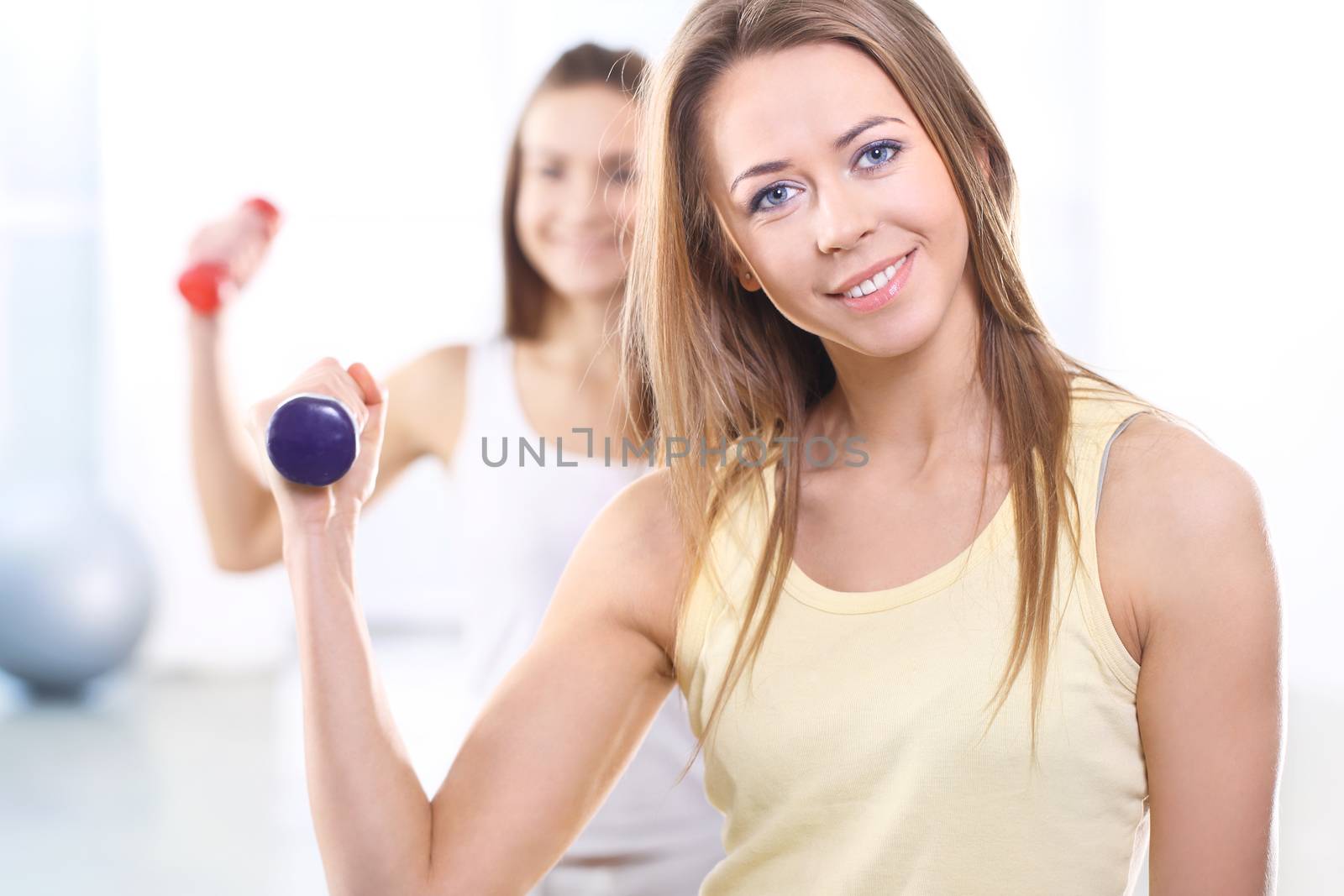 Training with weights, two young women in the gym by robert_przybysz