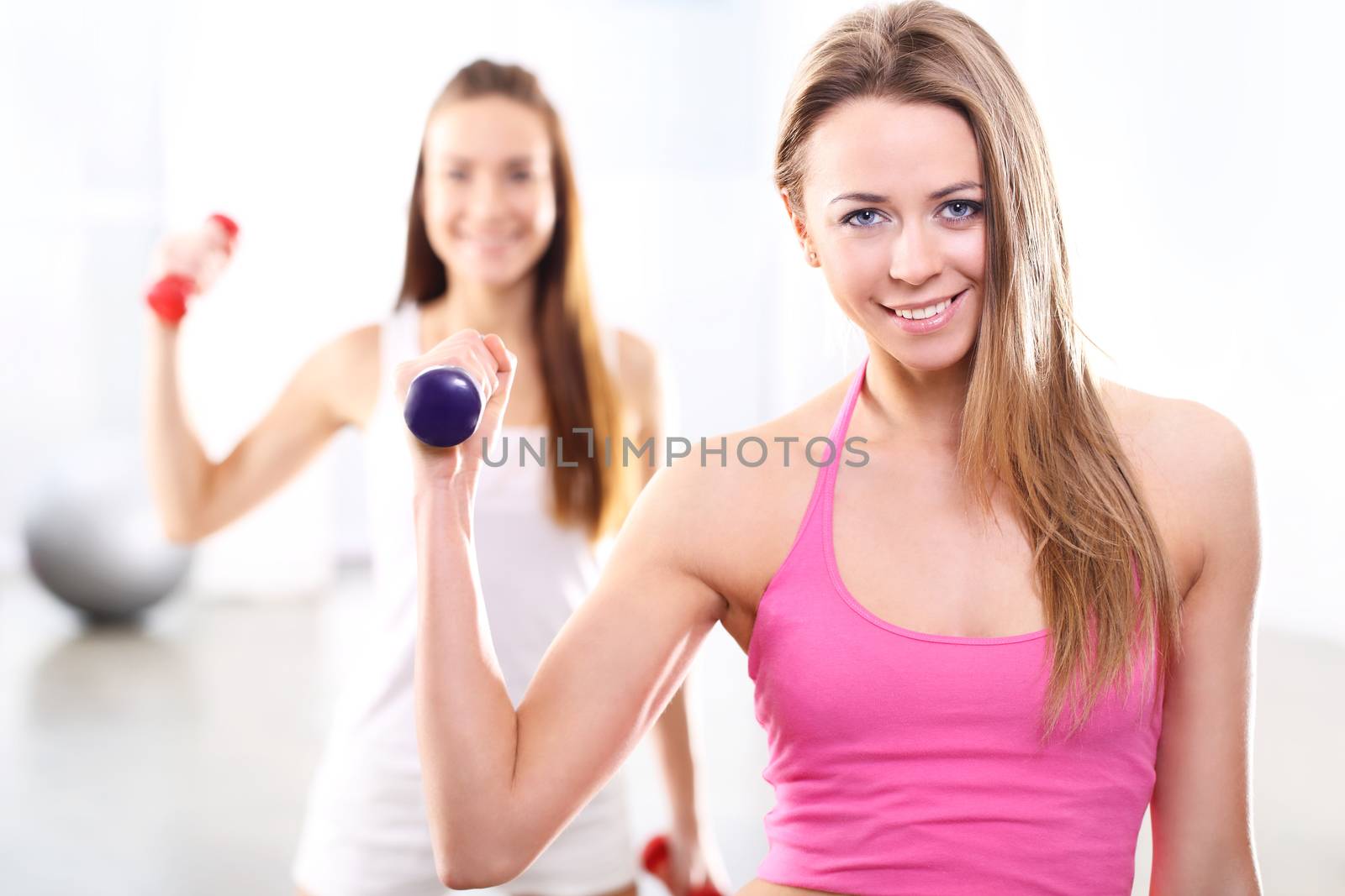 Training with weights, two young women in the gym by robert_przybysz