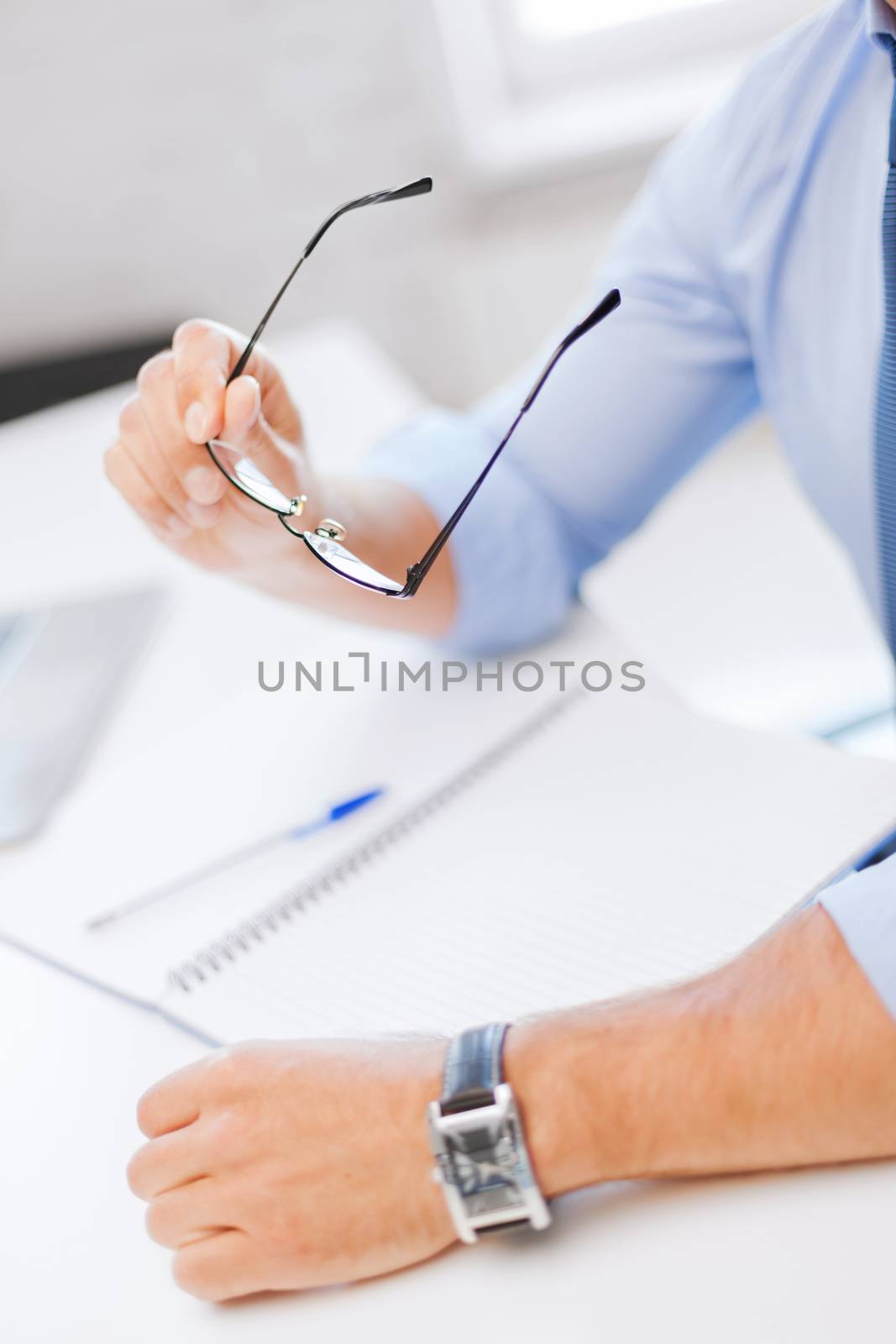 business, office, school and education concept - businessman with spectacles writing in notebook
