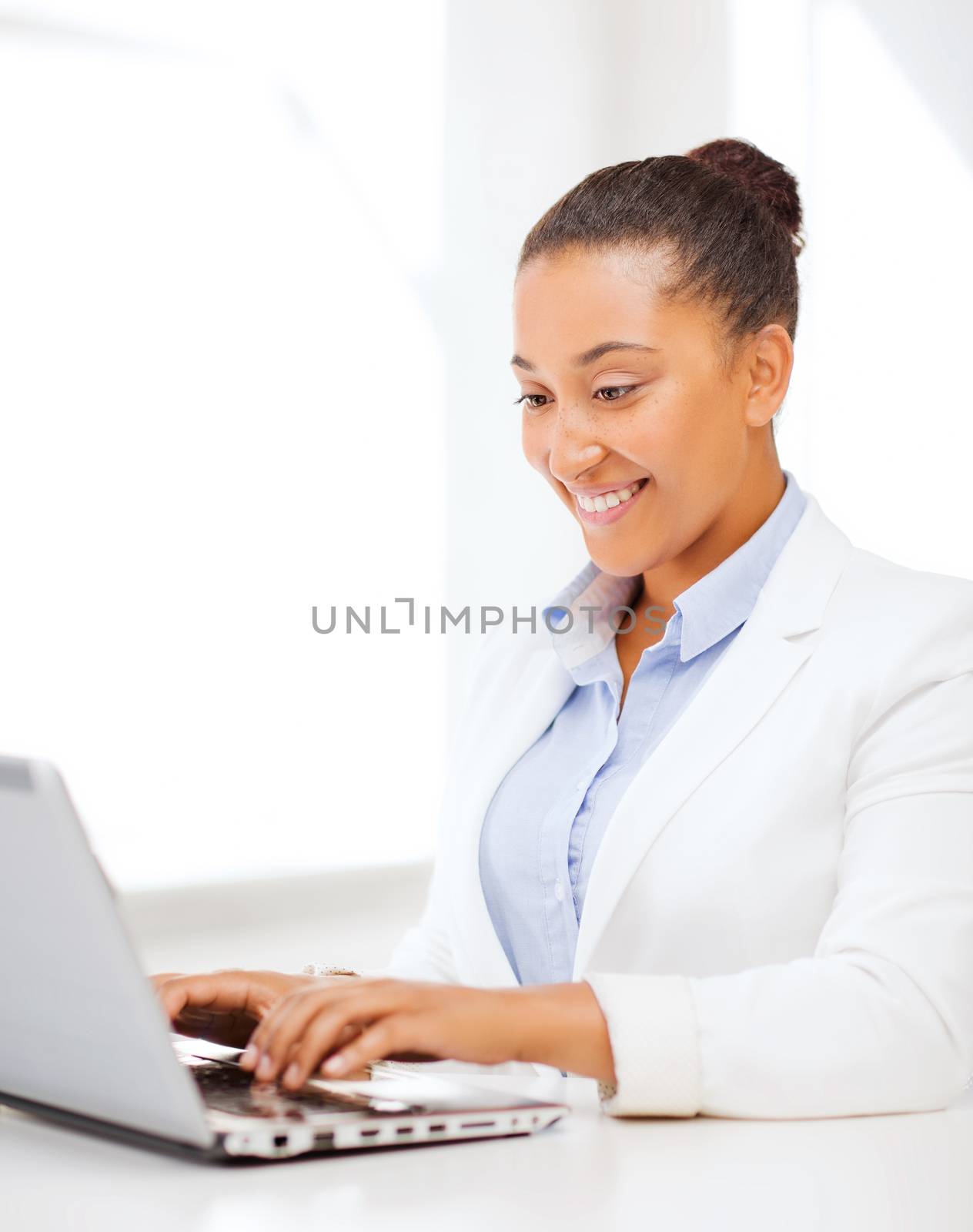 business and technology concept - african businesswoman with laptop in office
