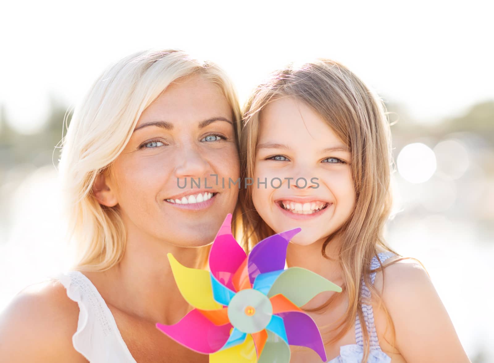 happy mother and child girl with pinwheel toy by dolgachov