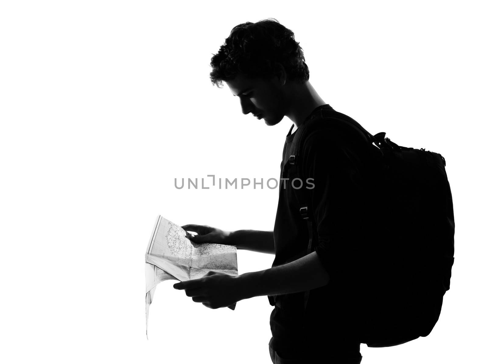 young man backpacker reading map silhouette in studio isolated on white background