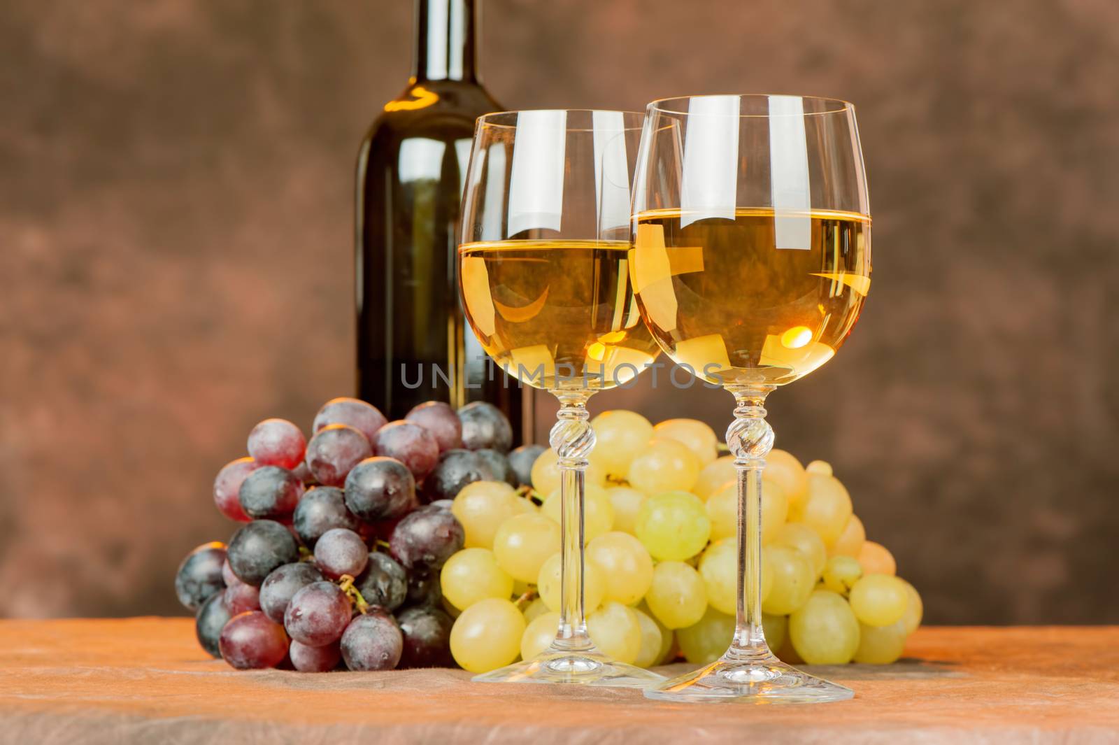 cups of white wine in front of grape and bottle