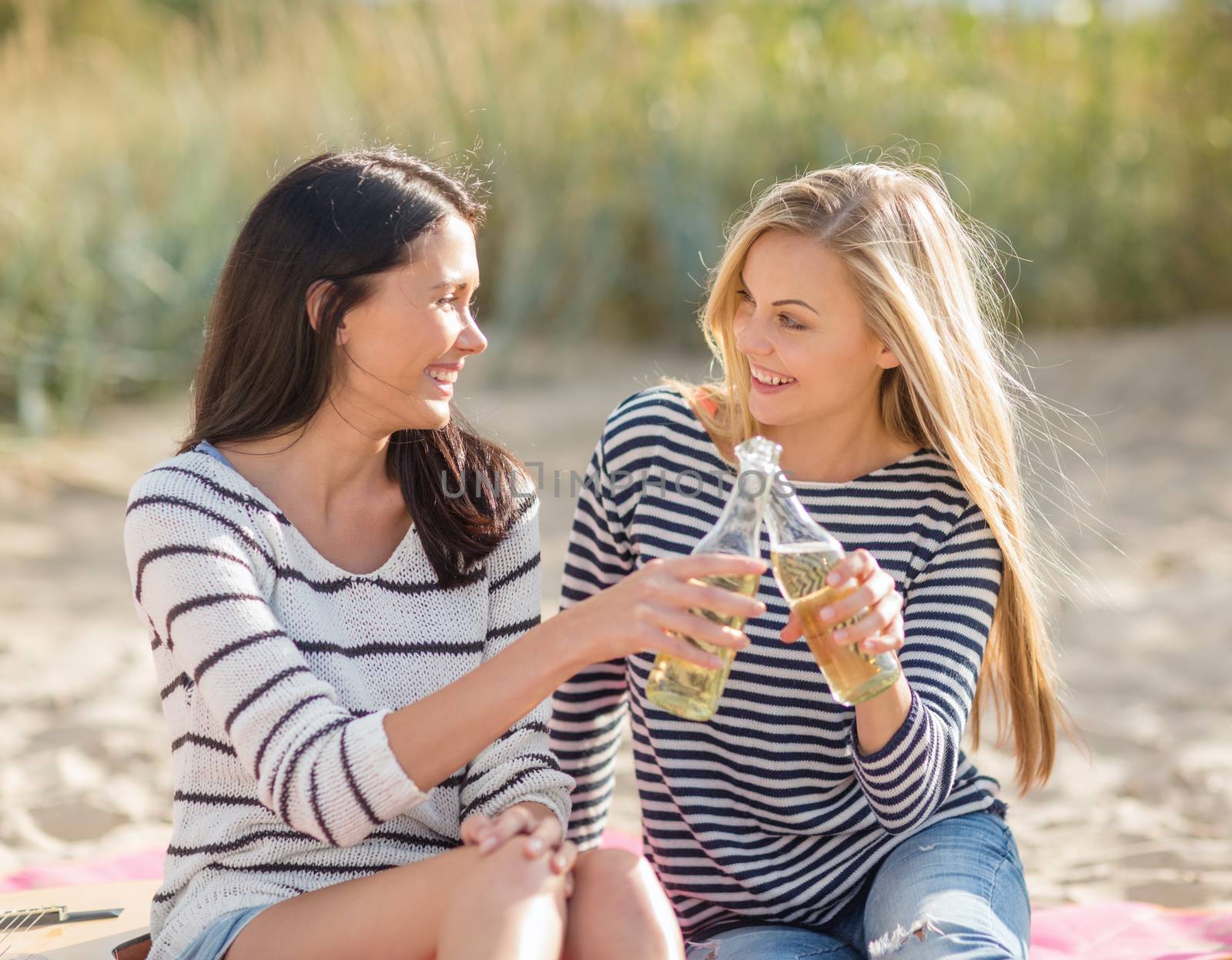 summer holidays and vacation concept - girls with drinks on the beach