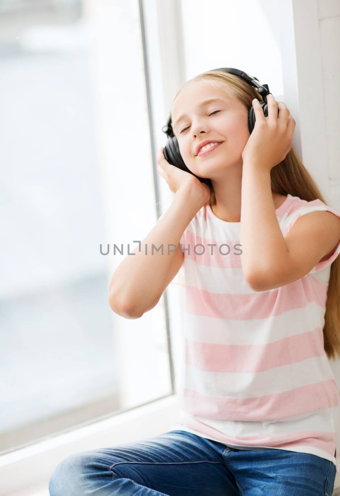 little girl with headphones at home by dolgachov