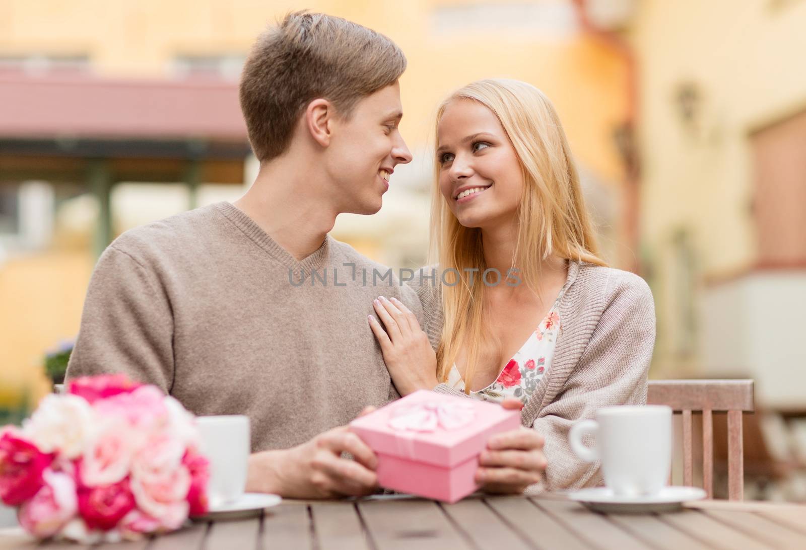 summer holidays, love, travel, tourism, relationship and dating concept - romantic happy couple with gift in the cafe