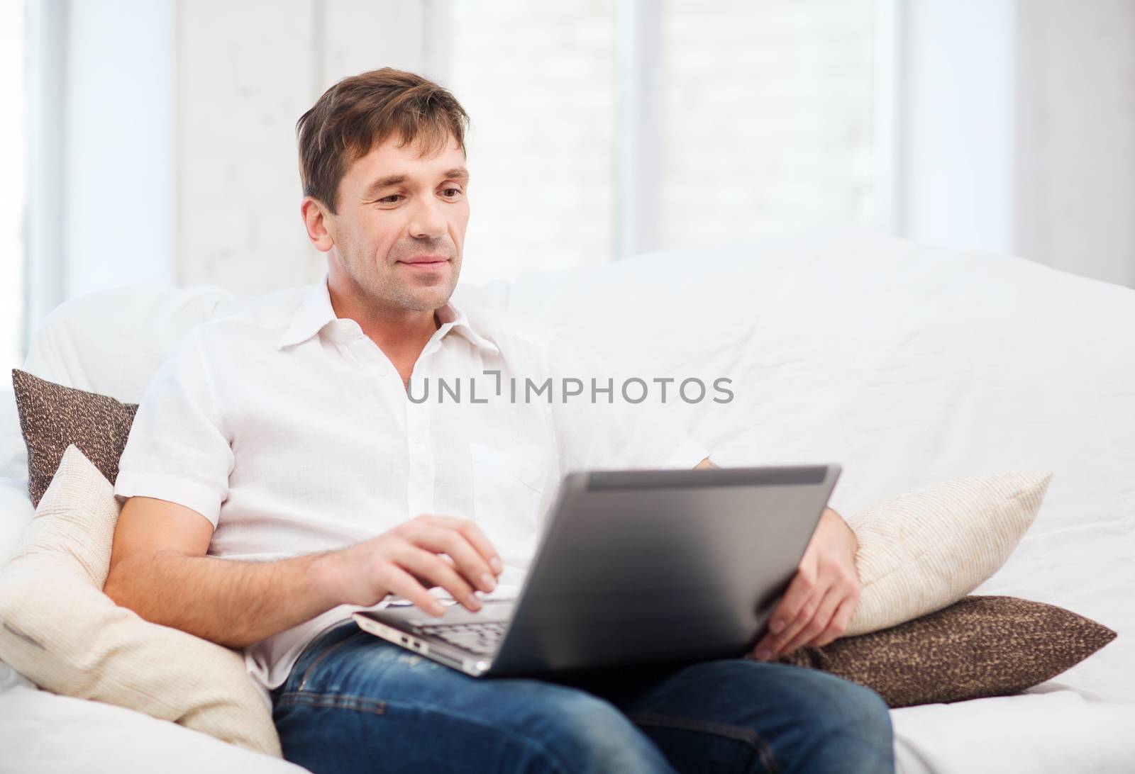man working with laptop at home by dolgachov