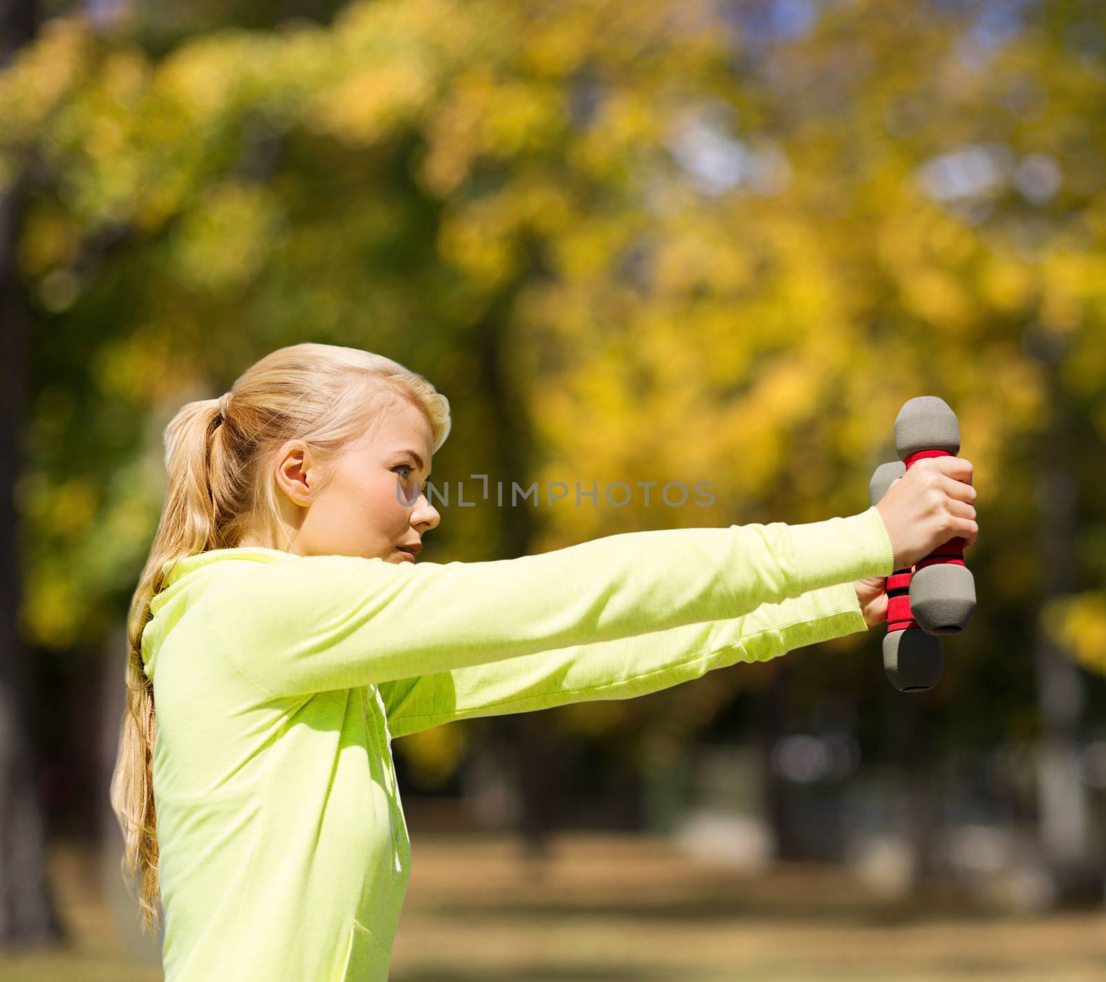 sporty woman with light dumbbells outdoors by dolgachov