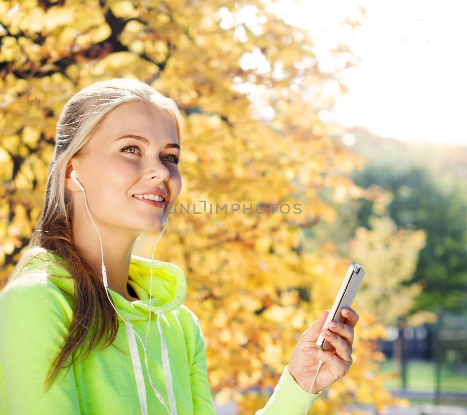 sport and lifestyle concept - woman doing sports and listening to music outdoors