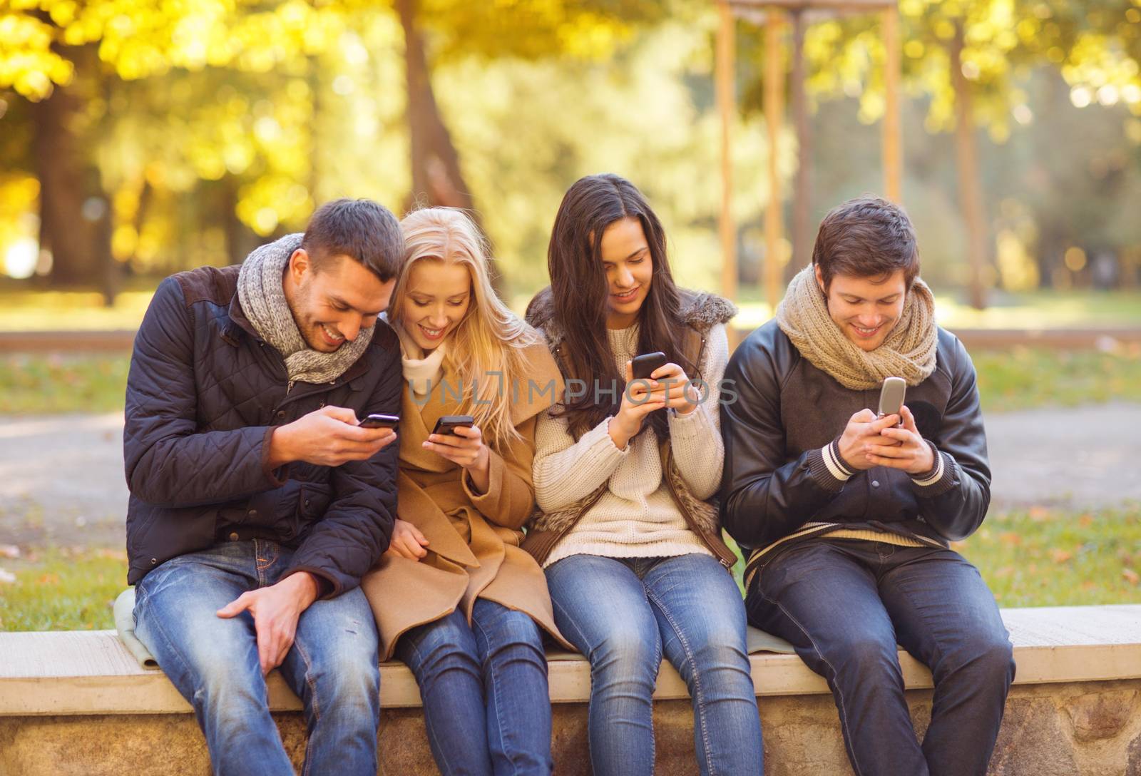 summer, holidays, vacation, happy people concept - group of friends or couples with smartphones having fun in autumn park