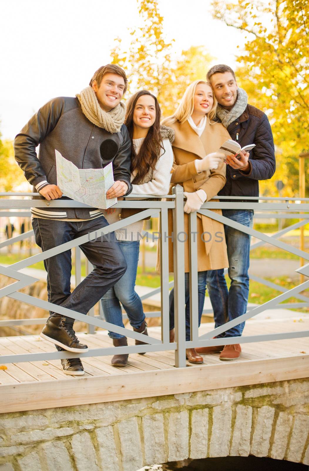 holidays and tourism concept - group of friends or couples with tourist map in autumn park