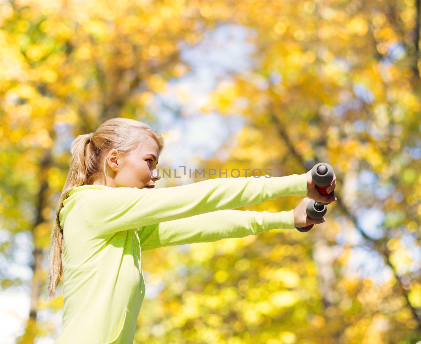 sport and lifestyle concept - young sporty woman with light dumbbells outdoors