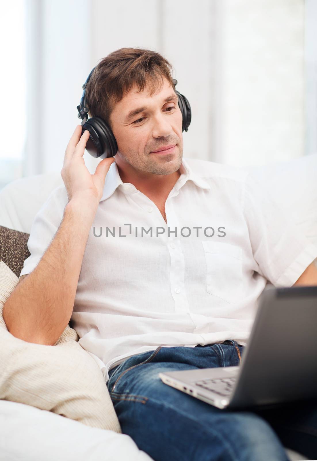 technology, leisure and lifestyle concept - happy man with headphones listening to music at home