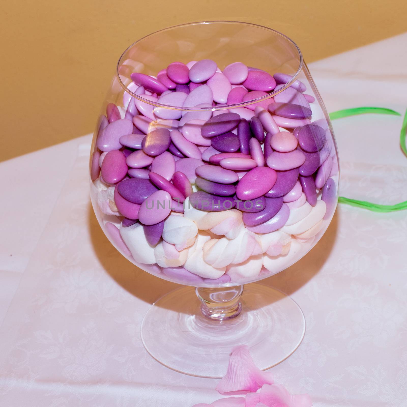 Glass vase full of colourful confetti, over a table