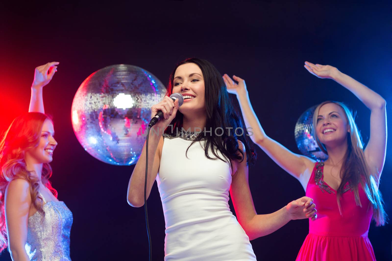 three smiling women dancing and singing karaoke by dolgachov