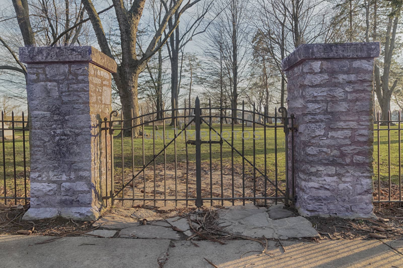 Gothic iron cemetery gates on brick posts. Bare trees in the background.