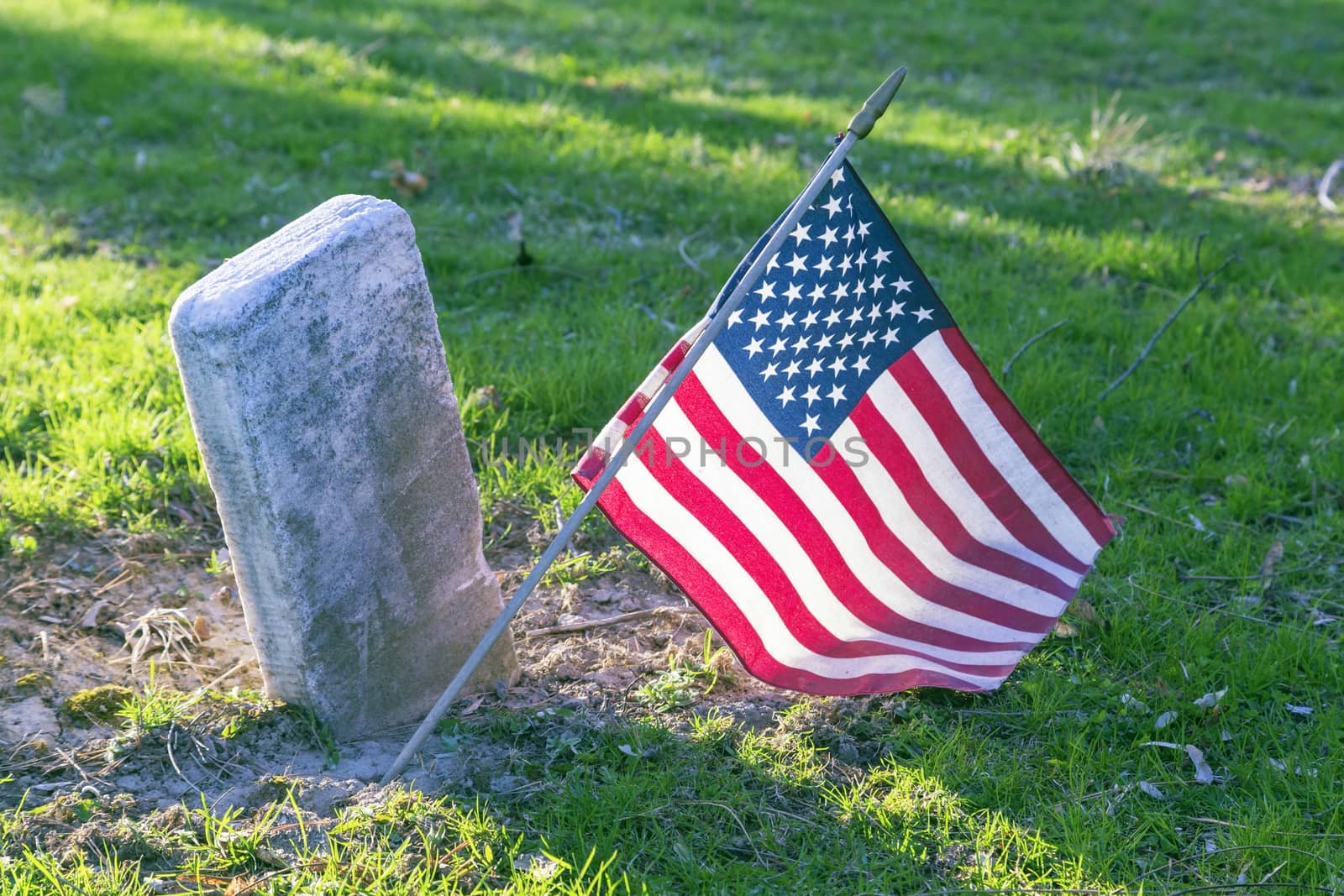 United States of America flag stuck in the ground at a soldiers grave. 
