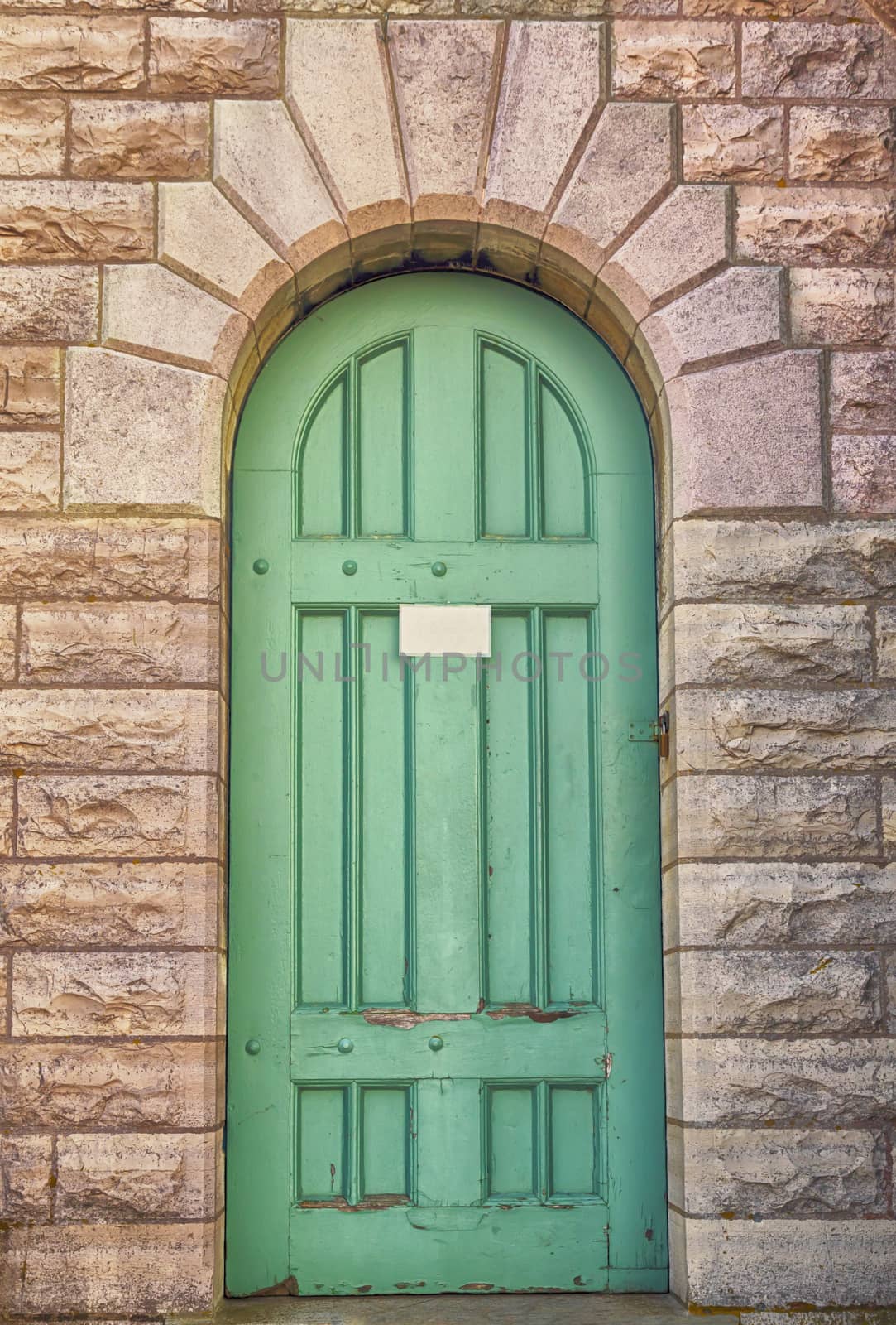 Intricate green door set in a brick design archway. 