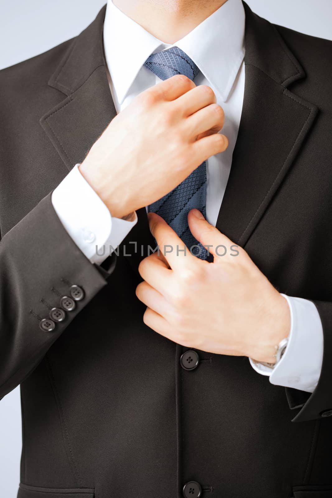 business people and office concept - close up of man adjusting his tie