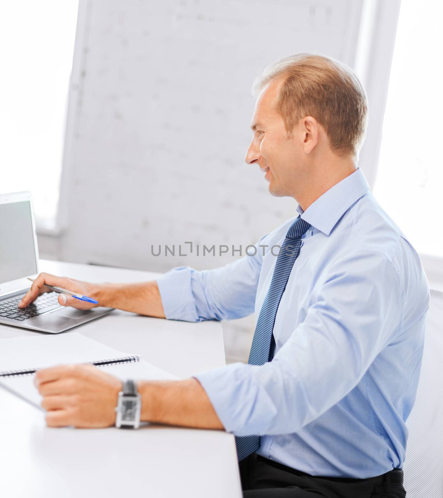 smiling businessman working in office by dolgachov