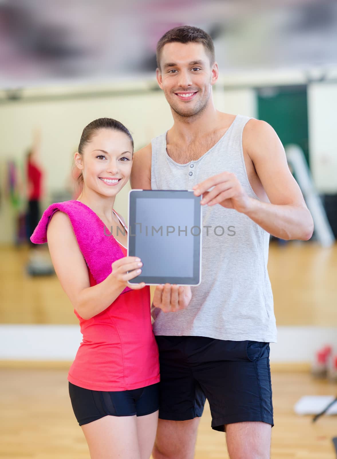 two smiling people showing blank tablet pc screen by dolgachov