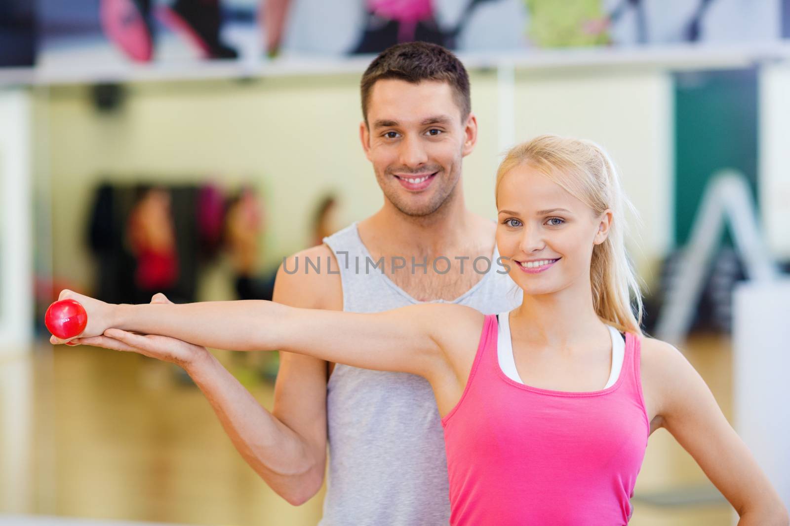 male trainer with woman working out with dumbbell by dolgachov