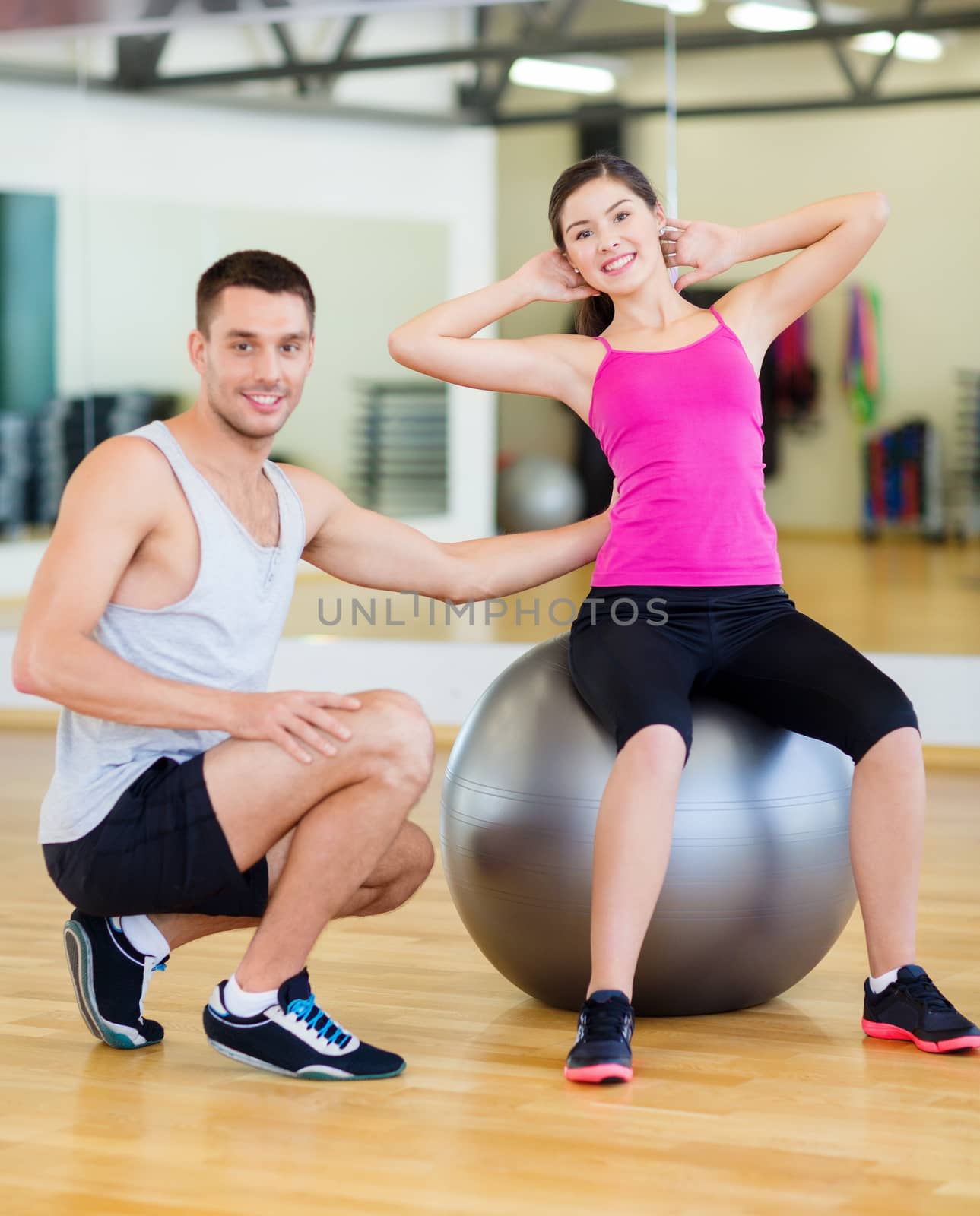 male trainer with woman doing crunches on the ball by dolgachov