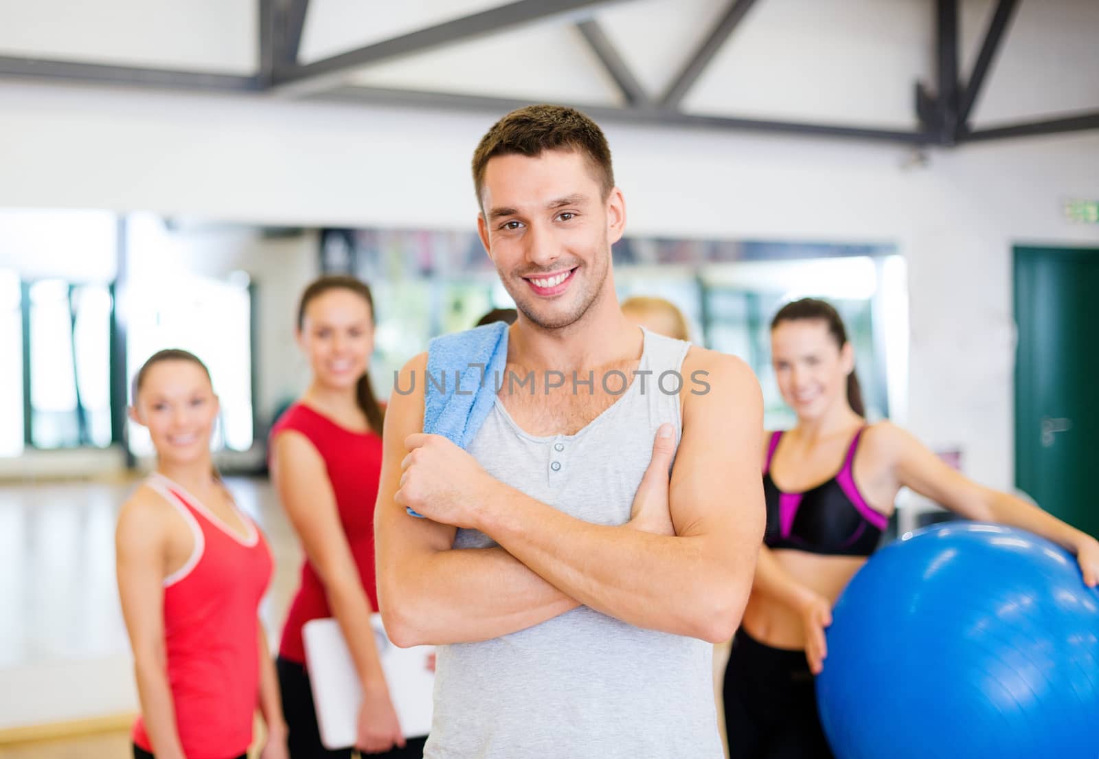 smiling man standing in front of the group in gym by dolgachov