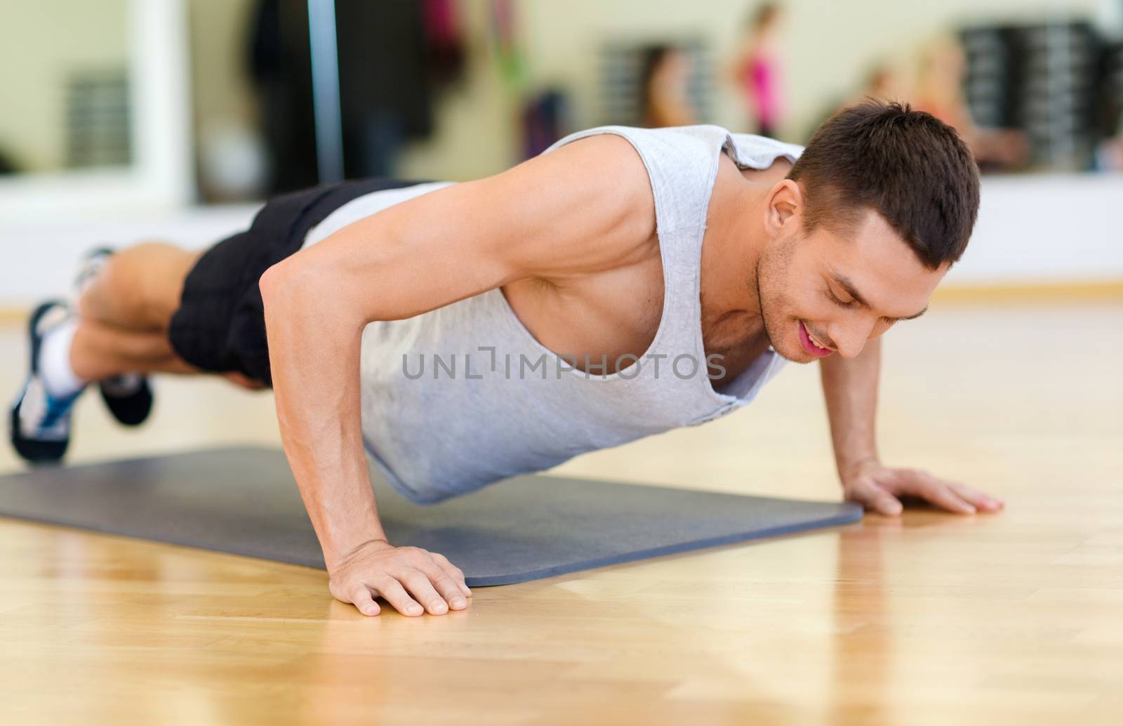 smiling man doing push-ups in the gym by dolgachov