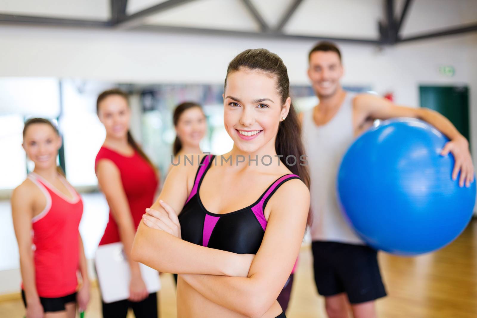 fitness, sport, training, gym and lifestyle concept - smiling woman standing in front of the group of people in gym