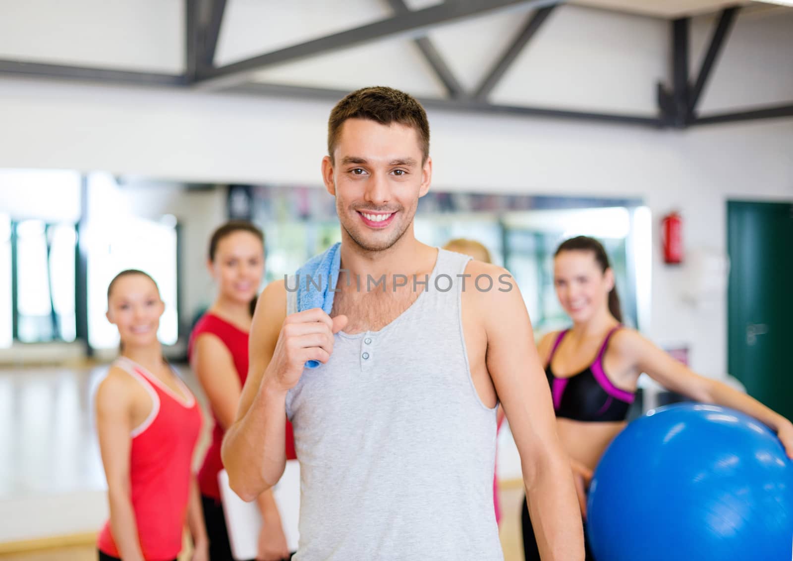 smiling man standing in front of the group in gym by dolgachov