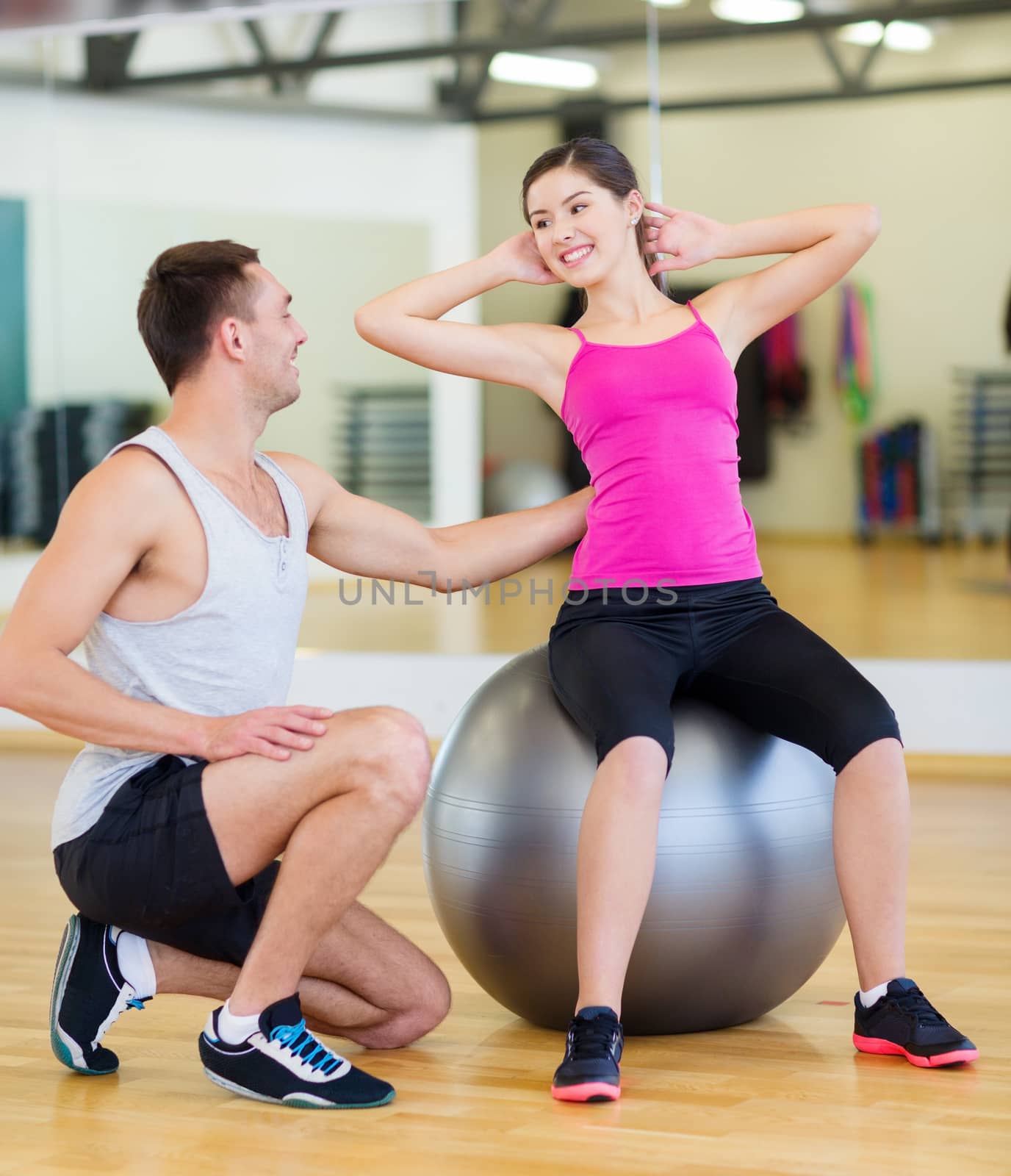 male trainer with woman doing crunches on the ball by dolgachov