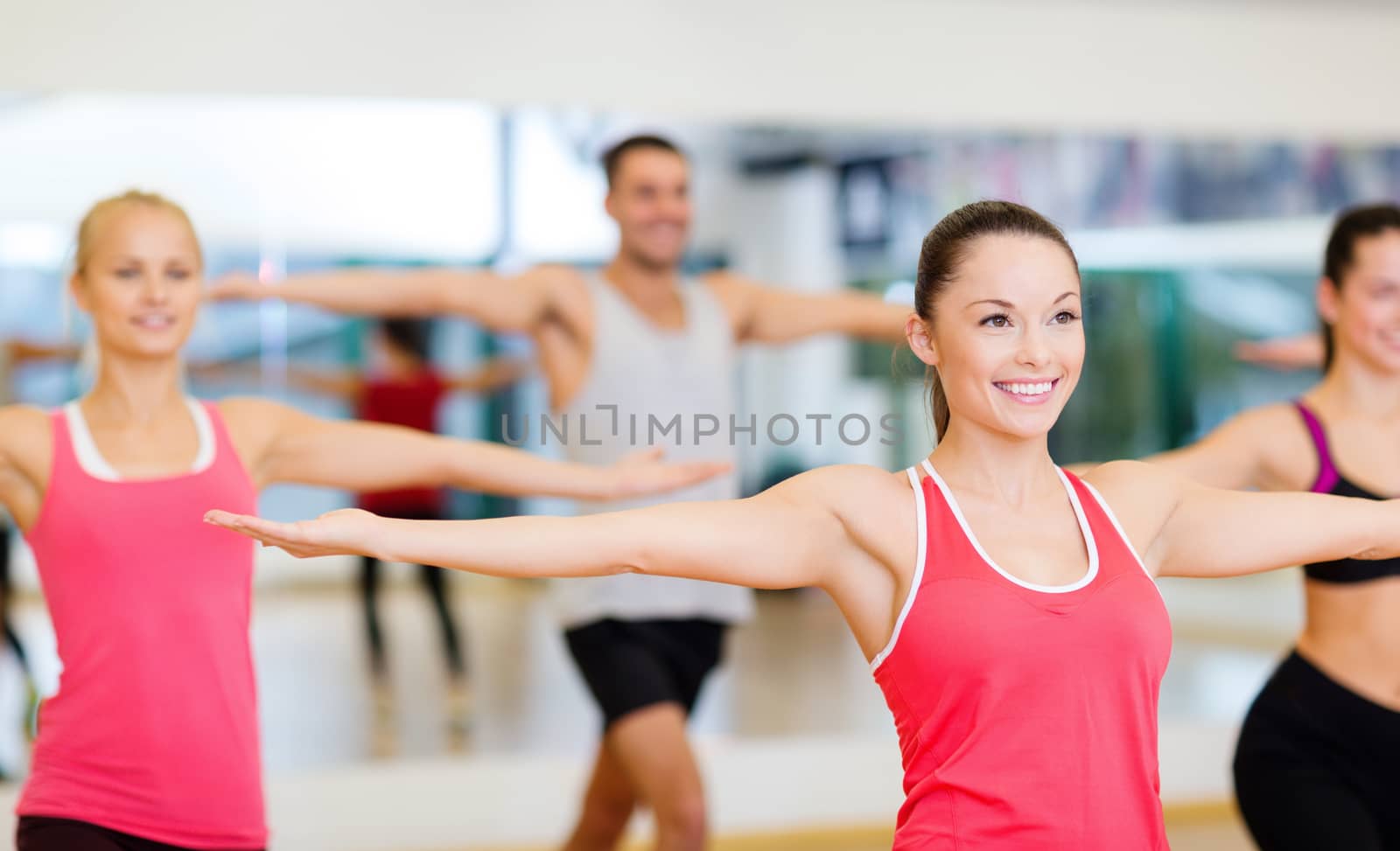 group of smiling people exercising in the gym by dolgachov