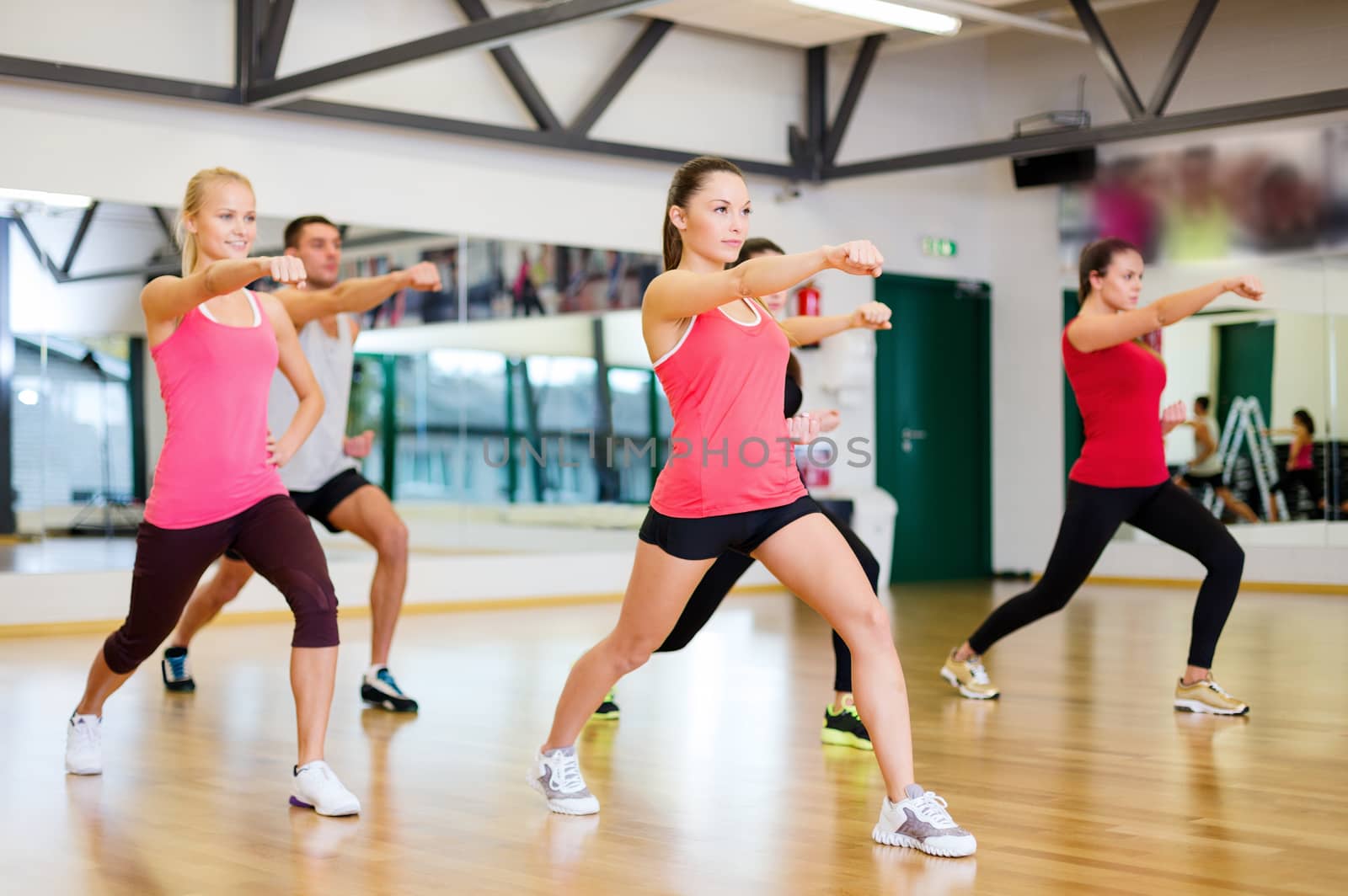 group of smiling people exercising in the gym by dolgachov