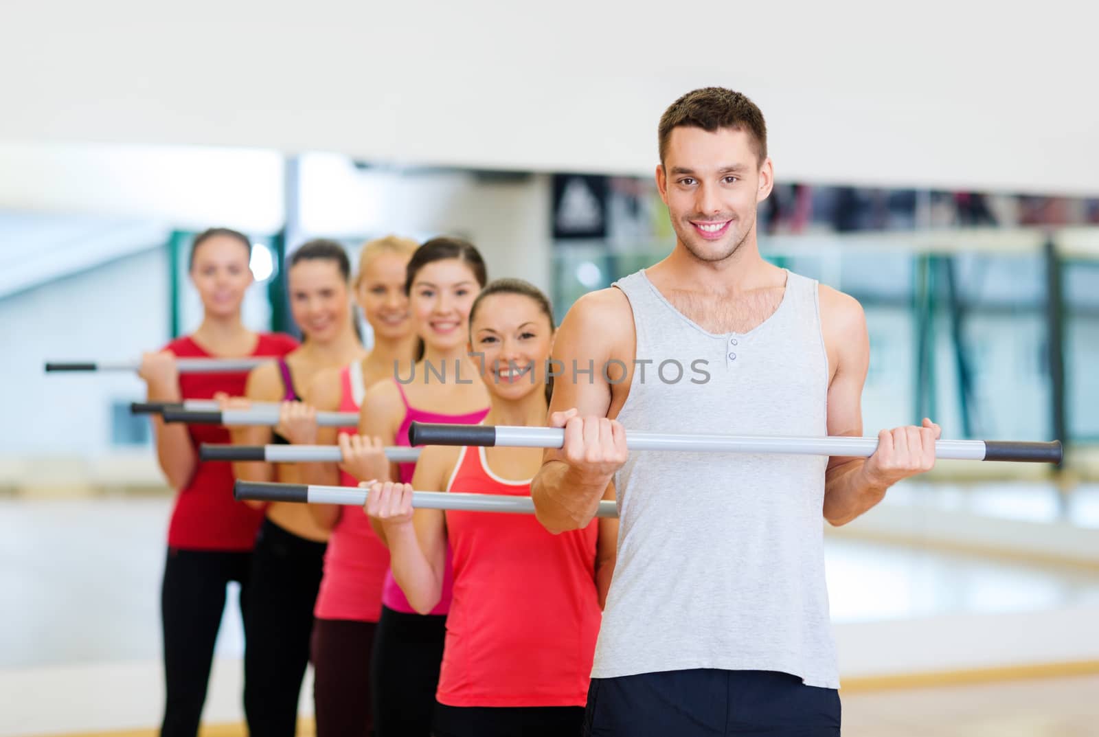 fitness, sport, training, gym and lifestyle concept - group of smiling people working out with barbells in the gym