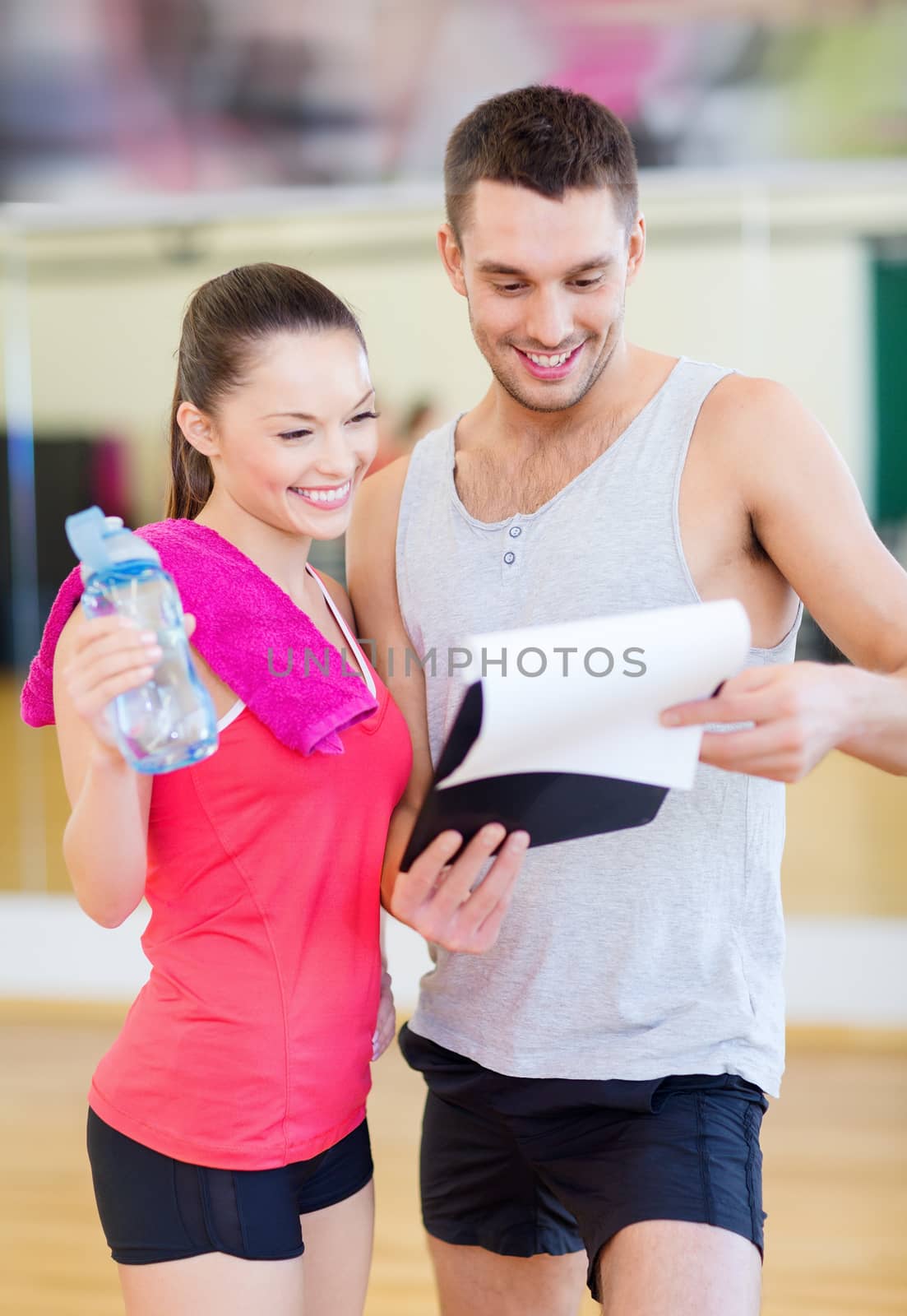 smiling male trainer with woman in the gym by dolgachov