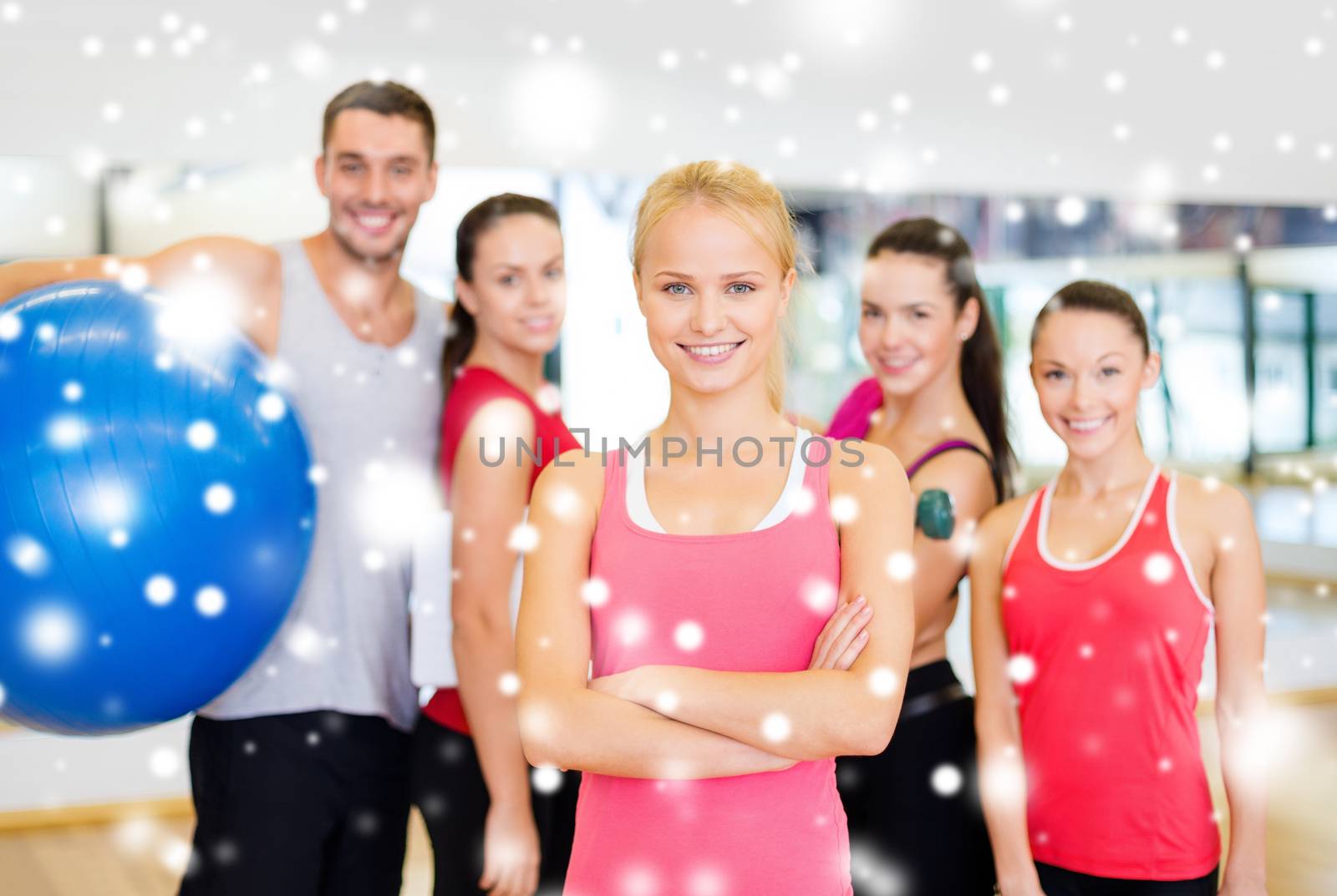 fitness, sport, training, gym and lifestyle concept - smiling woman standing in front of the group of people in gym