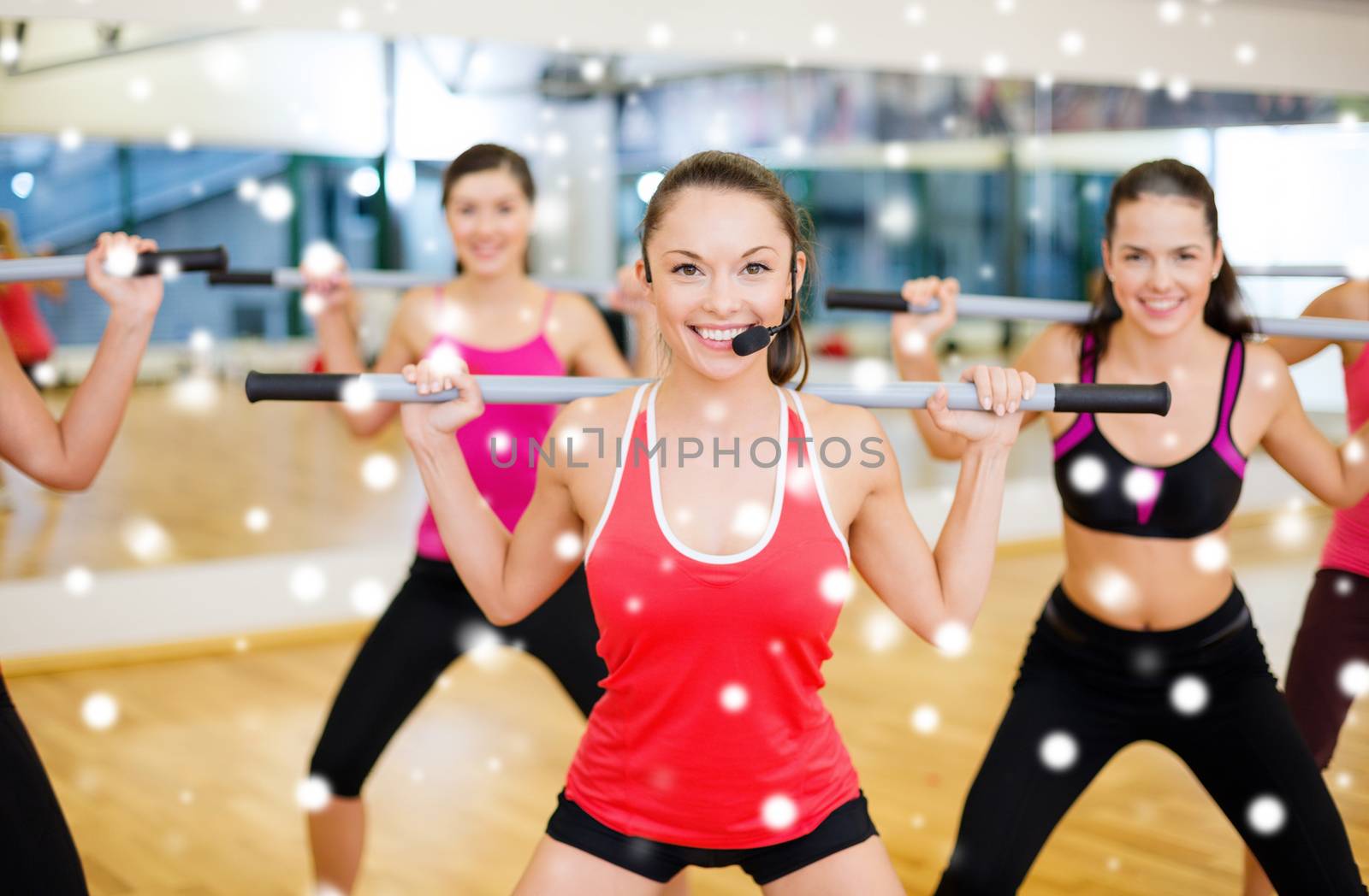 fitness, sport, training, gym and lifestyle concept - smiling trainer in front of the group of people working out with barbells in the gym