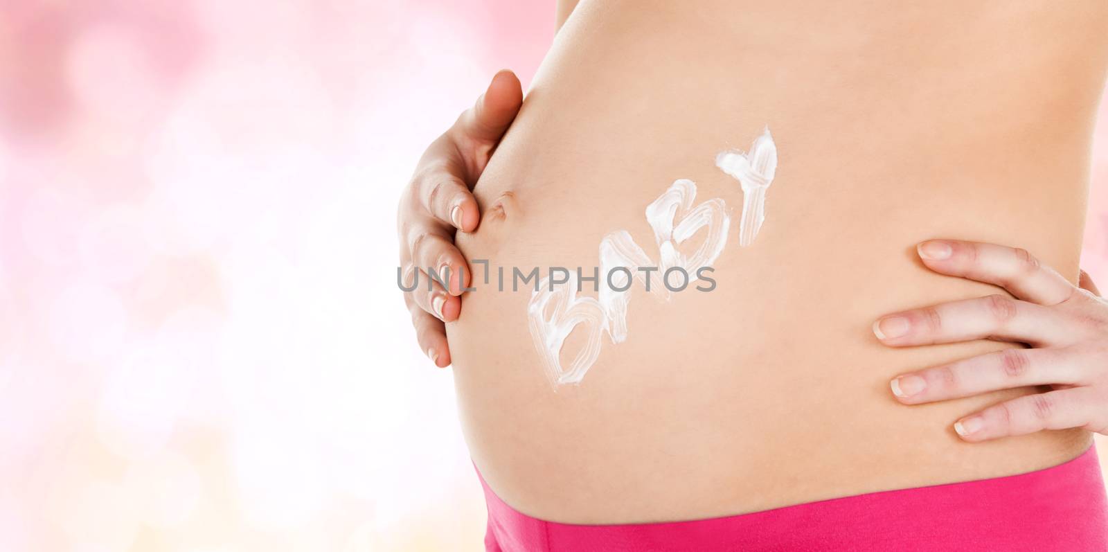 pregnancy, maternity and health concept - belly of a pregnant woman with cream