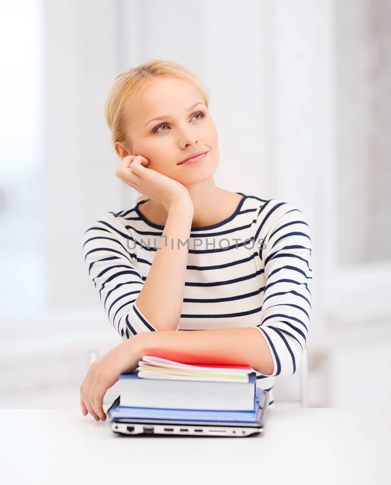 education and internet concept - dreaming student girl with laptop, books and notebooks in college